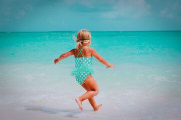 Wall Mural - happy little girl run and play with water on beach