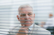 © yurolaitsalbert - close up. brooding elderly businessman standing in front of office window.