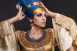 closeup studio portrait of a beautiful woman with brown eyes and evening make-up in the image of Queen Cleopatra, crown, necklace, golden dress