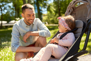 Poster - family, fatherhood and people concept - happy father with child in stroller at summer park