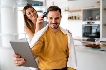 Couple having hair cut at home during quarantine coronavirus pandemic, online hairdressing on tablet