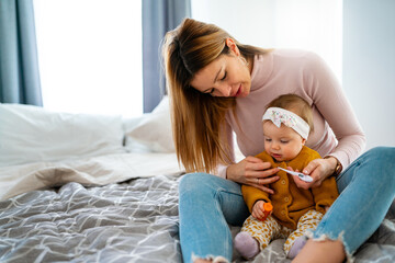 Wall Mural - Mother measuring temperature of her ill kid. Sick child with high fever, mother holding thermometer.