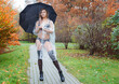 young woman in black lingerie, stockings and a transparent raincoat with an umbrella