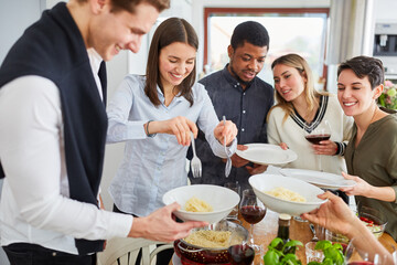 Wall Mural - Friends having meal together served spaghetti in shared kitchen