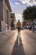 black afro american man with yellow sweatshirt turned back walking down city street with sun in background