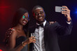 © Seventyfour - Waist up portrait of elegant African-American couple taking selfie photo while enjoying party
