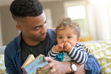 young african-american man reading book story to baby girl