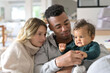 © goodluz - Young mixed-raced family at home cuddling baby girl