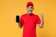 © ViDi Studio - Delivery employee african man in red cap blank print t-shirt uniform workwear work courier service concept hold in hand using mobile cell phone free space screen isolated on yellow background studio.