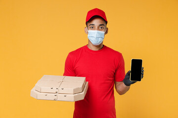 Wall Mural - Delivery employee african man in red cap blank print tshirt face mask gloves work courier service on quarantine coronavirus covid19 virus hold pizza flatbox mobile phone isolated on yellow background