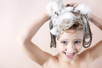 Wall Mural - adorable little girl with blue eyes washing her hair in the bathroom and laughs, foam on the head, l