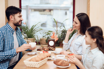 Wall Mural - Young Happy Family Eating Cakes in Cafeteria.