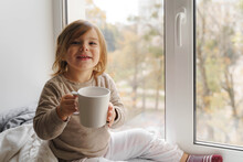 Child Drink Cocoa Or Milk Near The Window From Big White Mug. Mock Up Of Cup. Christmas Time