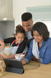 © goodluz - Happy family in home kitchen making american cookies looking at recipe online