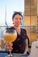 Wall Mural - Woman having a drink with Dubai city view