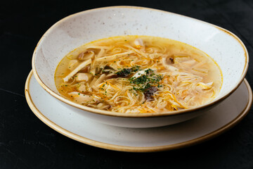 Wall Mural - chicken broth with noodles on a textured black background