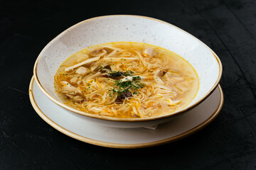 Wall Mural - chicken broth with noodles on a textured black background