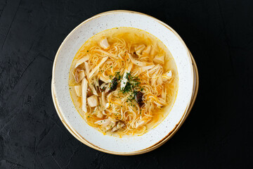 Wall Mural - chicken broth with noodles on a textured black background