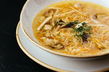 Wall Mural - chicken broth with noodles on a textured black background
