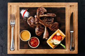 Wall Mural - grilled lamb rack with vegetables and sauce on a black backgroun