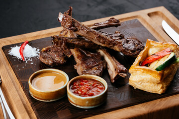 Wall Mural - grilled lamb rack with vegetables and sauce on a black backgroun