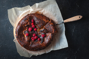 Wall Mural - Burnt hot cheese cake out of the oven on the parchment or baking paper at the black background.