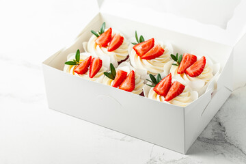 Wall Mural - Chocolate cupcakes with white whipped cream top decorated with strawberries cut in the white gift box