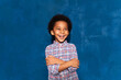 Joyful african kid boy laughing at humor joke on blue studio background, overjoyed cute black child with afro hair having fun enjoy laughter and sincere positive emotions. Body language concept.