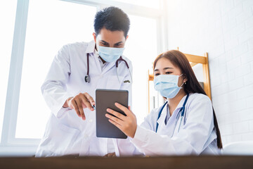 Asian Medical healthcare doctor colleague teamwork working together examine diagnosing discussing using tablet wearing surgical mask work at home modern office wireless online technology communication