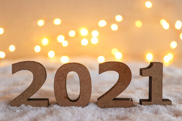 Beautiful New Year background with selective focus. Numbers 2021 against festive blurred background with bokeh. New Year's holiday concept. Close up, copy space for congratulation