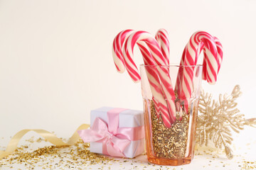 Christmas candy canes, gift box and confetti on beige background, space for text