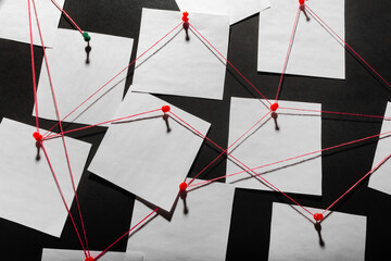 Photo of a black detecftive board with blank paper linked by red thread.
