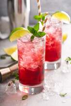 Cranberry Lime Cocktails In Tall Glasses Served With Ice, A Slice Of Lime And Fresh Mint