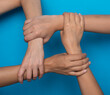© Prostock-studio - Unrecognizable Women Holding Hands Symbolizing Togetherness, Blue Background, Cropped