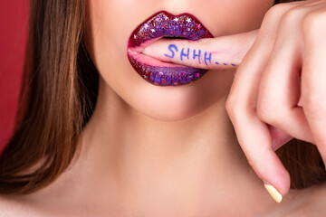 Wall Mural - Shhh woman. Shh, Womens secrets. Female with finger in mouth. Closeup of young woman is showing a sign of silence with shhh written on the finger.