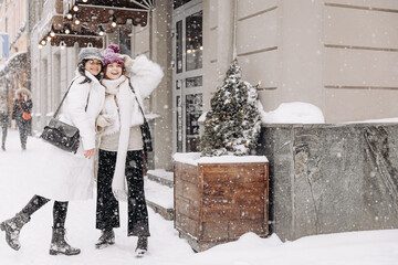 Female friends in warm outfit posing on camera outside