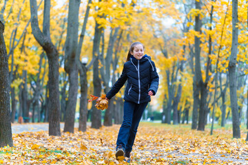 Wall Mural - a girl running through the park and enjoys autumn, beautiful nature with yellow leaves