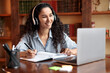 © Prostock-studio - Woman sitting at desk, using laptop and writing in notebook