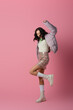 © LIGHTFIELD STUDIOS - brunette young woman in stylish winter outfit dancing on pink background