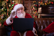 © FOTO_STOCKER - Christmas online congratulations from Santa. Santa Claus using notebook laptop for distance Christmas call kids sitting near Christmas tree at home. Happy New Year Covid 2021.