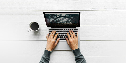 Wall Mural - man using a laptop on a wooden table aerial view