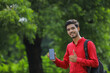 © PRASANNAPIX - Young indian college student showing smart phone over nature background