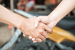 © Odua Images - close up of both hands shaking hands against the background of the motorbike in the tire repair shop