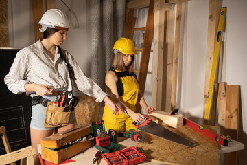 Two girls start in the workshop preparing the tools to start the working day on the construction site. Carpentry tools.