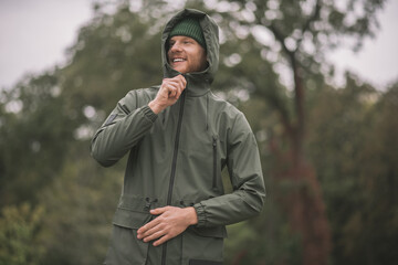 Young man in a green coat standing in the rain