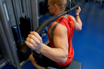 Wall Mural - sport, fitness and bodybuilding concept - close up of man exercising with cable machine in gym