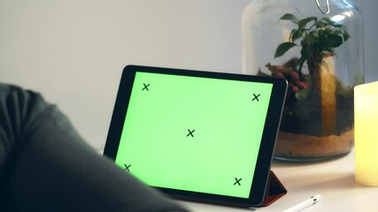 Young Man looking at tablet with green screen enoying cup of tea. Close up shot of watching tablet.