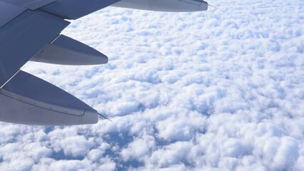 Wall Mural - commercial airliner flying over clouds with blue sky in the background. travel and artistic concept