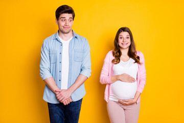 Wall Mural - Photo of optimistic young couple stand pregnant woman wear casual outfits isolated on yellow color background