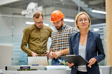 portrait of leading female architectural engineer artist working with colleagues creating design with scale model home in the background ,coworking